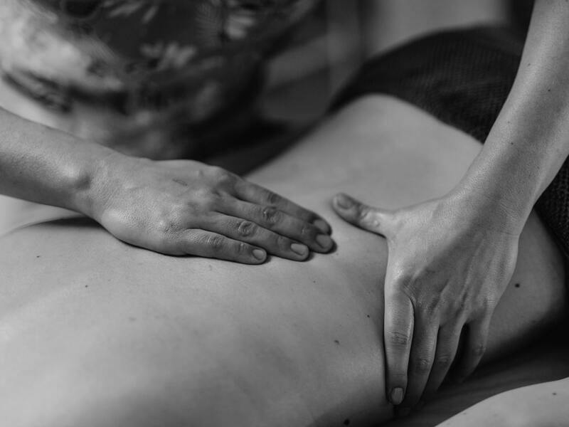A person receiving a back massage, showing a therapist’s hands applying pressure on the lower back